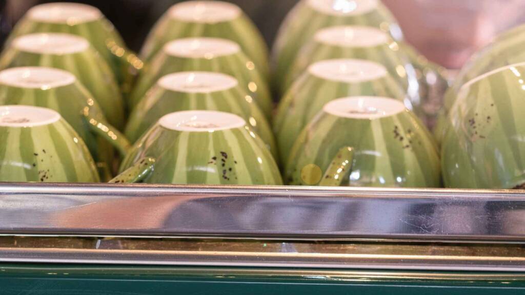 Green, biodegradable coffee cups stacked, showcasing Avocado & Coffee's eco-conscious packaging.